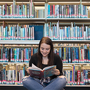 Student reading book in library (image)